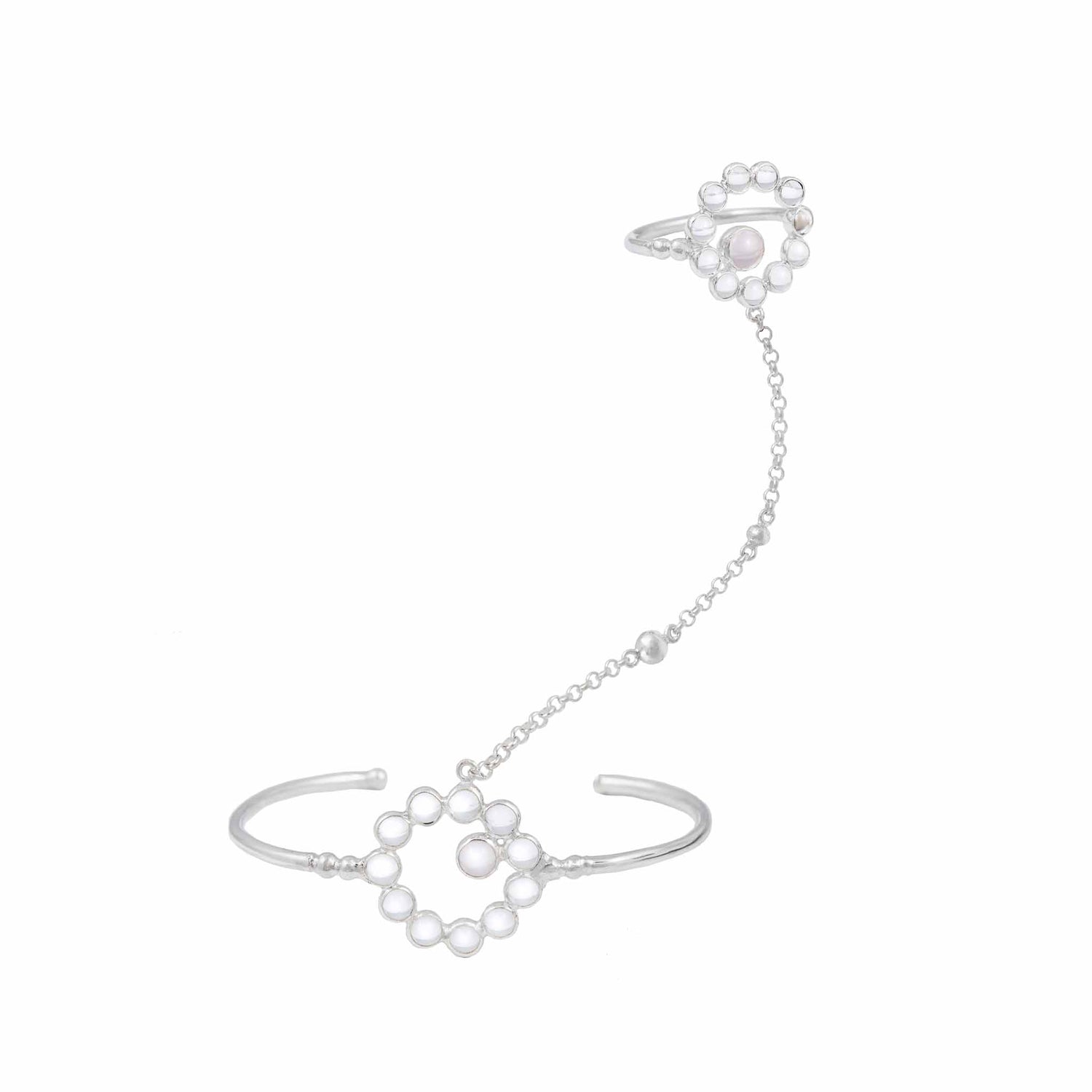 The Silver Hand Chain Me with Crystal & Rose Quartz by Kaora Sandara Jewelry is a striking hand chain bracelet featuring a circular floral motif adorned with white pearls. It connects to a matching ring via a delicate chain, with each piece showcasing the same floral design and pearls at the center, embodying the essence of self-acceptance jewelry.