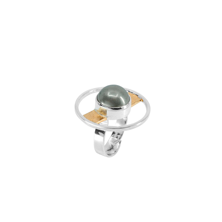 The Animus Ring – Sterling Silver & Gold-Plated with Pyrite by Kaora Sandara Jewelry showcases a round green-grey Pyrite stone at its center, set within an open, circular design. A thin, horizontal golden bar elegantly connects the band and stone, adding a unique, modern touch that exudes masculine qualities.
