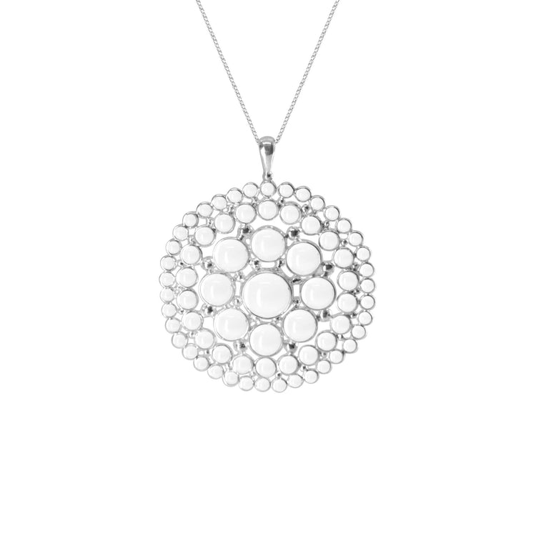 The Purity Pendant by Kaora Sandara Jewelry is a Sterling Silver 925 necklace which features a large circular pendant adorned with transparent rhinestone crystals. The intricately designed pendant showcases several concentric circles made up of smaller circles, giving it a unique and elegant appearance.