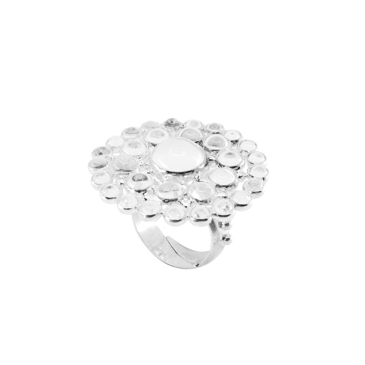 A ring from the Purity series, size L, made of silver. It is round in shape, featuring small round rock crystal stones and a single large central round rock crystal. Top view on a white background.